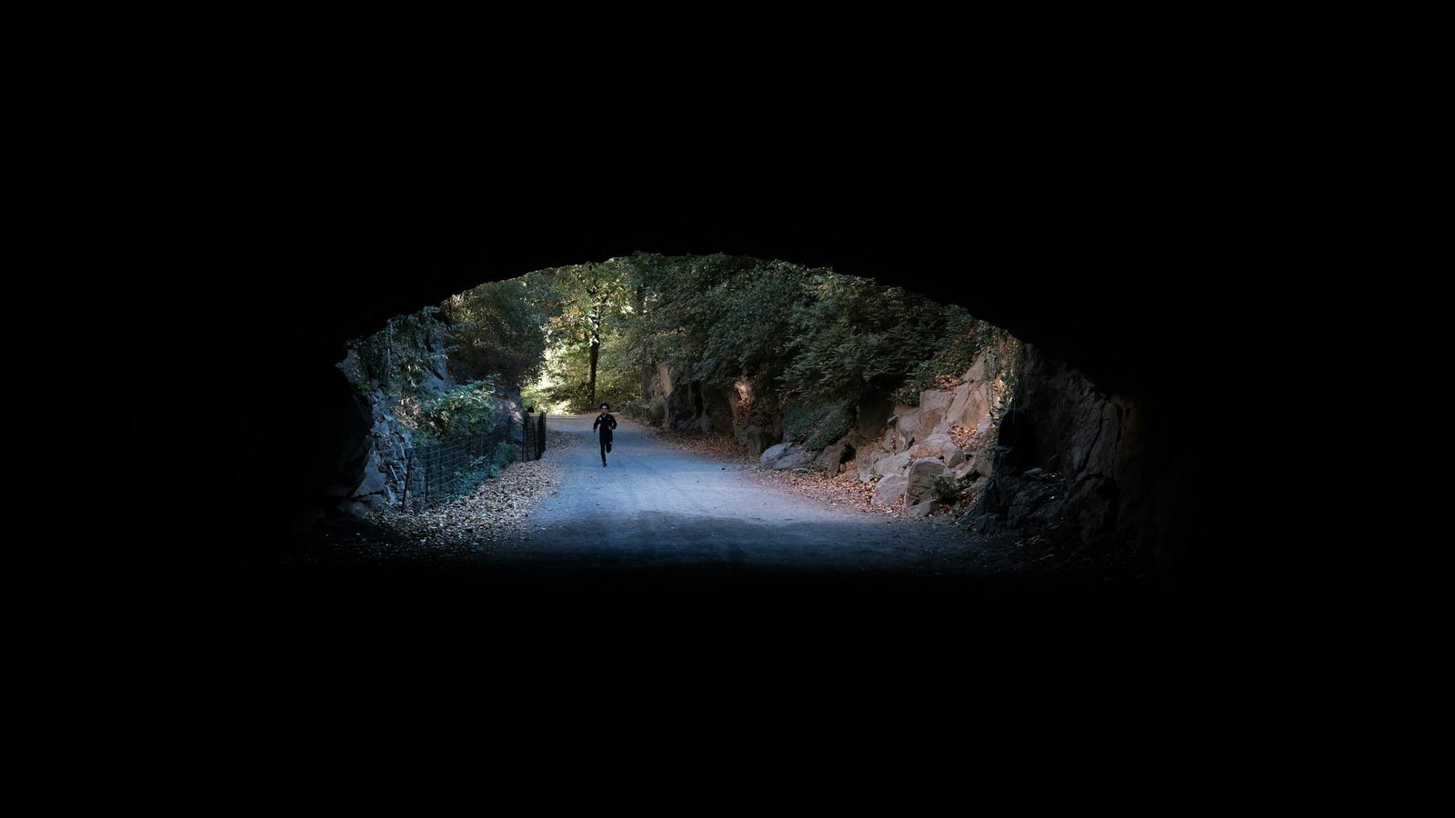 A dark tunnel with a person walking through it